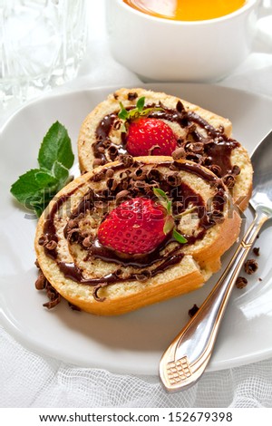 Chocolate swiss roll cake with strawberries on the white plate