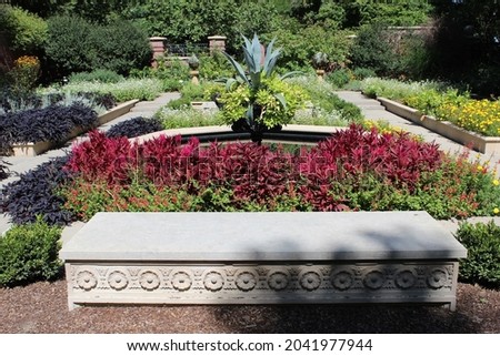 Photograph of large concrete decorative stone bench in front of colorful landscaped garden of plants and flowers during the day in the sun light. Full color photo. ストックフォト © 