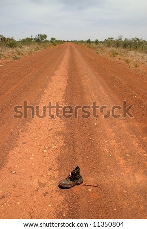 Australian red rural road with an obsolete shoe on the middle of road. Tanami road, Western Australia