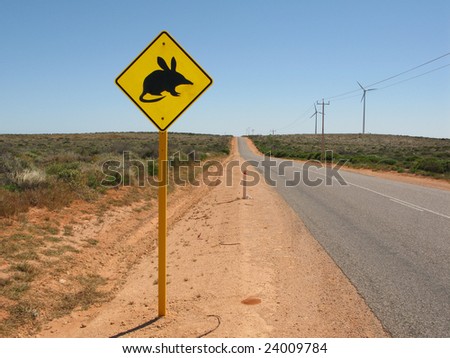 Warning bandicoot road sign standing beside a road in Western Australia. In background electric generating windmills. Australia