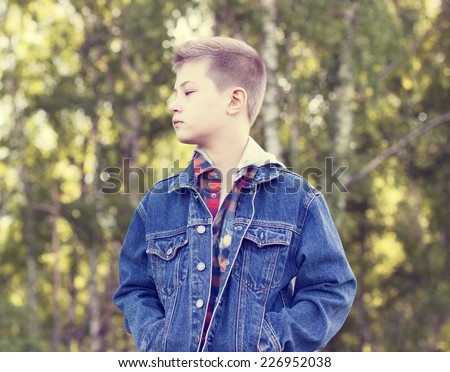 A boy stands in the park and looks into the distance