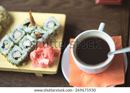 Closeup photo of sushi and rolls a mug of hot coffee or tea on the table, breakfast or dinner in the cafe.