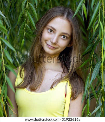 Portrait of beautiful girl close-up in the open air, in the trees, smiling happily enjoying the bright summer day, resting student teenager.