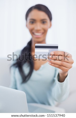 Cheerful pretty woman in bright living room using her laptop to buy online