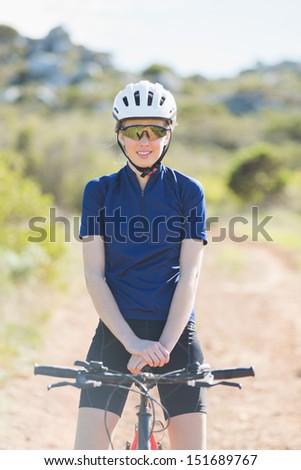Woman with helmet sitting on bike looking at camera