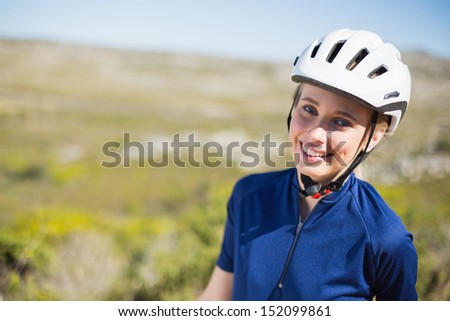 Woman wearing helmet smiling at camera on a sunny day