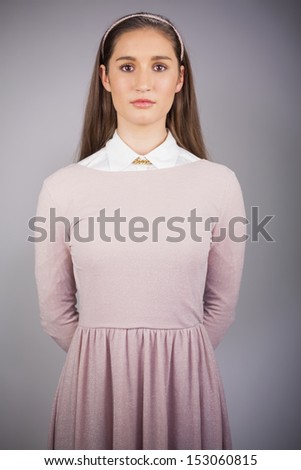 Serious pretty model with pink dress on posing on grey background