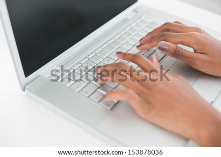 Close up on woman\'s hands typing on her laptop in bright fitness studio