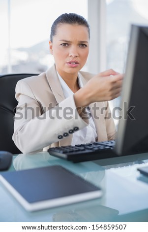 Worried sophisticated businesswoman working on computer in bright office