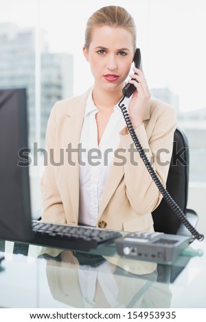 Frowning pretty businesswoman answering the phone in bright office