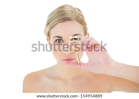 Concentrated young blonde woman using eyelash curler on white background