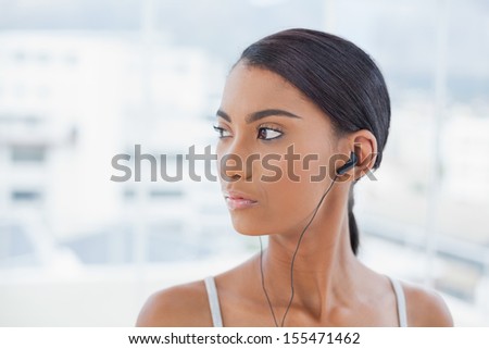 Pensive pretty model listening to music in bright room at home