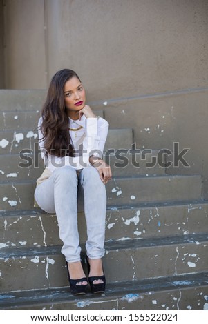 Attractive woman with red lips sitting on stairs outdoors on a bright day