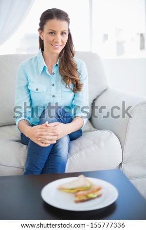 Calm pretty woman sitting on sofa in bright living room