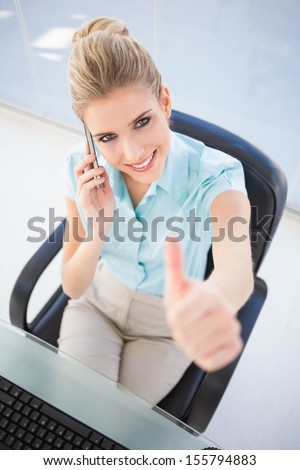 High angle view of smiling businesswoman on the phone giving thumb up in bright office