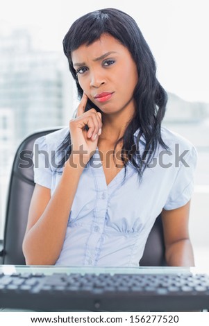 Thinking businesswoman looking at her computer in office