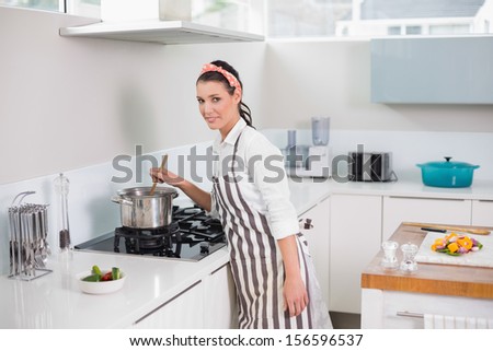 Smiling pretty woman with apron cooking in bright kitchen