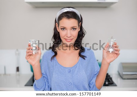 Smiling gorgeous model holding salt and pepper in bright kitchen