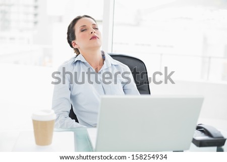 Sleepy stylish brunette businesswoman relaxing at her desk in bright office