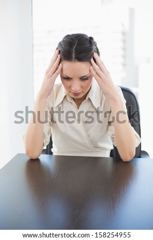 Nervous stylish brunette businesswoman holding her head in bright office