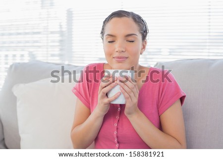 Peaceful woman enjoying a coffee break on the sofa at home
