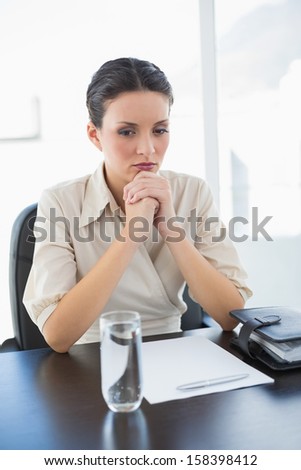 Upset stylish brunette businesswoman joining her hands in bright office
