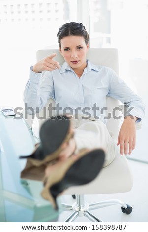 Frowning stylish brunette businesswoman relaxing with feet up in bright office