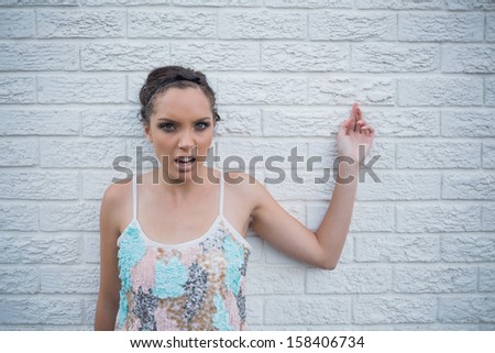 Angry woman leaning against a white wall and looking at camera
