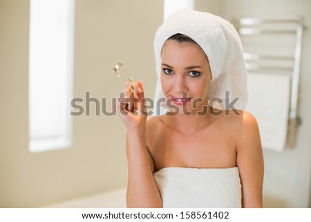 Happy natural brown haired woman using eyelash curler in a bright bathroom