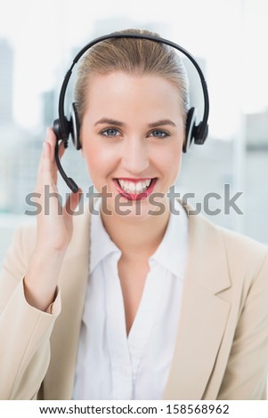 Smiling pretty call center agent in bright office wearing headset