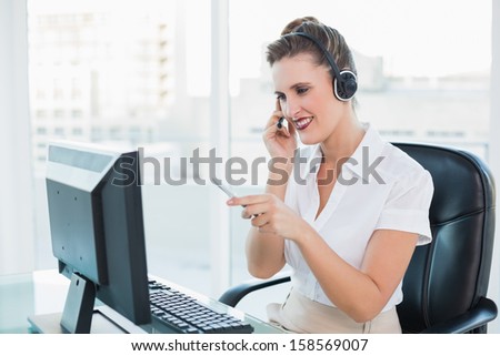 Smiling call center agent pointing at something on computer screen in bright office