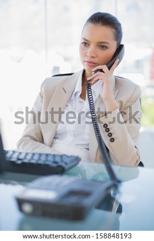 Pensive gorgeous businesswoman answering the phone in bright office