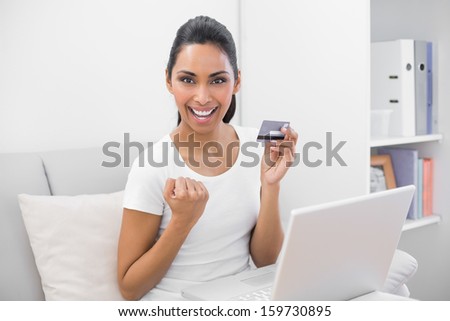 Beautiful successful woman home shopping with her notebook sitting in bright living room