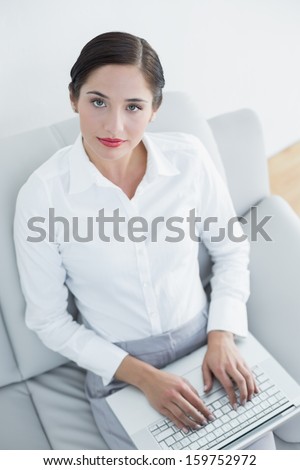 Portrait of a well dressed young woman using laptop on sofa at home