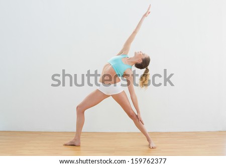 Calm slim blonde standing in high lunge pose in bright room