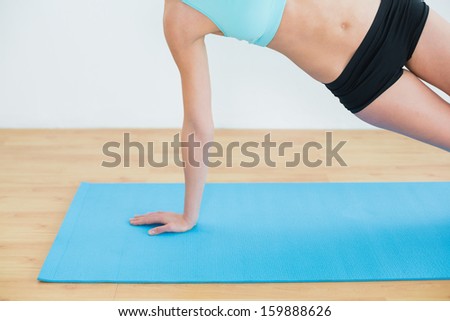 Close-up of a slim young woman doing the side plank yoga pose in fitness studio