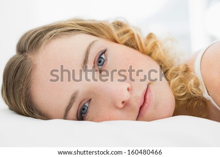Pretty content blonde lying in bed resting in bright bedroom