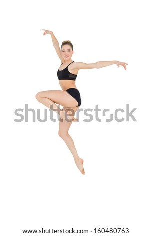 Smiling slim ballet dancer jumping in the air on white background