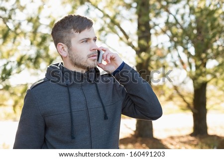 Serious young man using mobile phone in the forest