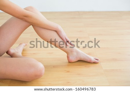 Close-up of a woman\'s toned legs and hand at fitness studio