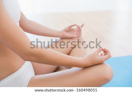 Close-up of a slim cropped woman in lotus pose at fitness studio