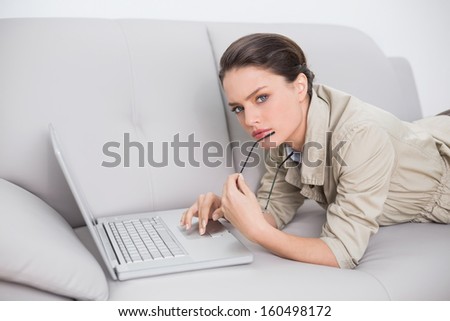 Side view portrait of a beautiful young woman using laptop on sofa at home