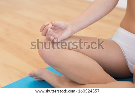 Close-up of a slim cropped woman in lotus pose at fitness studio