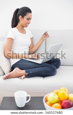 Happy woman home shopping sitting on couch in bright living room