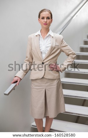 Unsmiling stylish businesswoman standing with hand on hip on the stairs