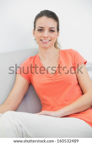 Beautiful casual woman posing sitting on couch smiling at camera