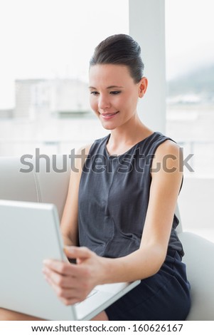 Beautiful well dressed young woman using laptop on sofa at bright home