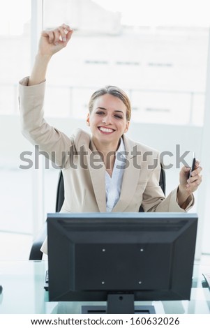 Content blonde businesswoman cheering sitting on her swivel chair looking at camera