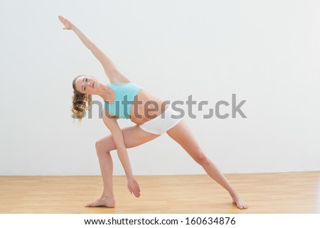 Calm slim blonde standing in extended side angle pose in bright room