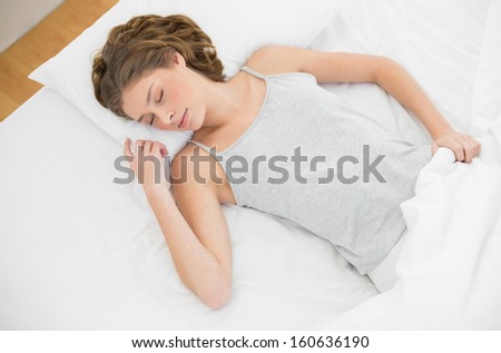 Calm slender woman lying sleeping on her bed under the cover in her bedroom